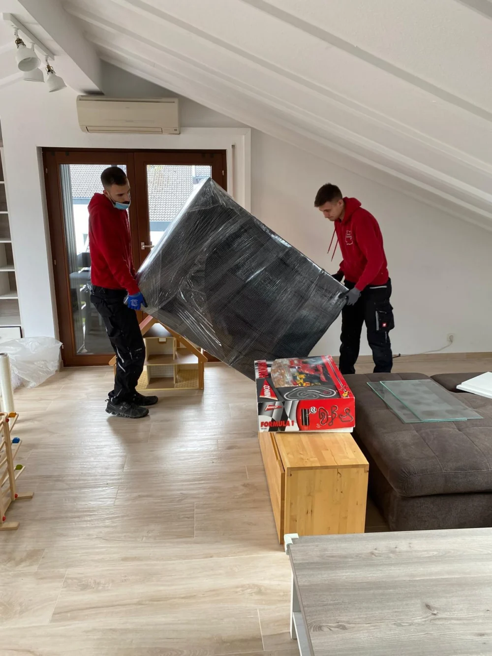 Möbelpacker von Sehic Umzüge tragen bei einem Privatumzug in Karlsruhe ein sorgfältig eingepacktes Möbelstück durch den Wohnraum